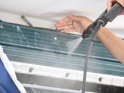 Technician cleaning air conditioner indoor unit filter in Dubai home for better cooling performance