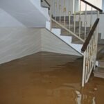 Technician repairing a submersible sump pump in a flooded Dubai basement drainage pit