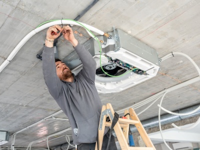 Technician inspecting VAV box in a Dubai office commercial AC system